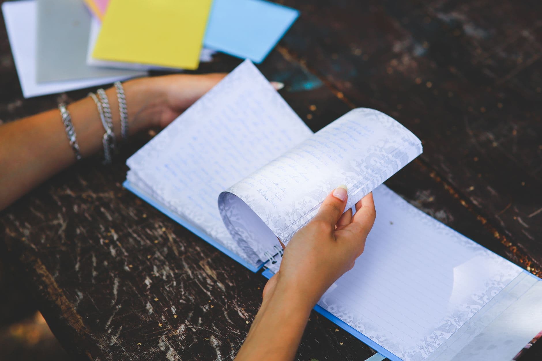 A person sitting at a table, writing by hand in a journal